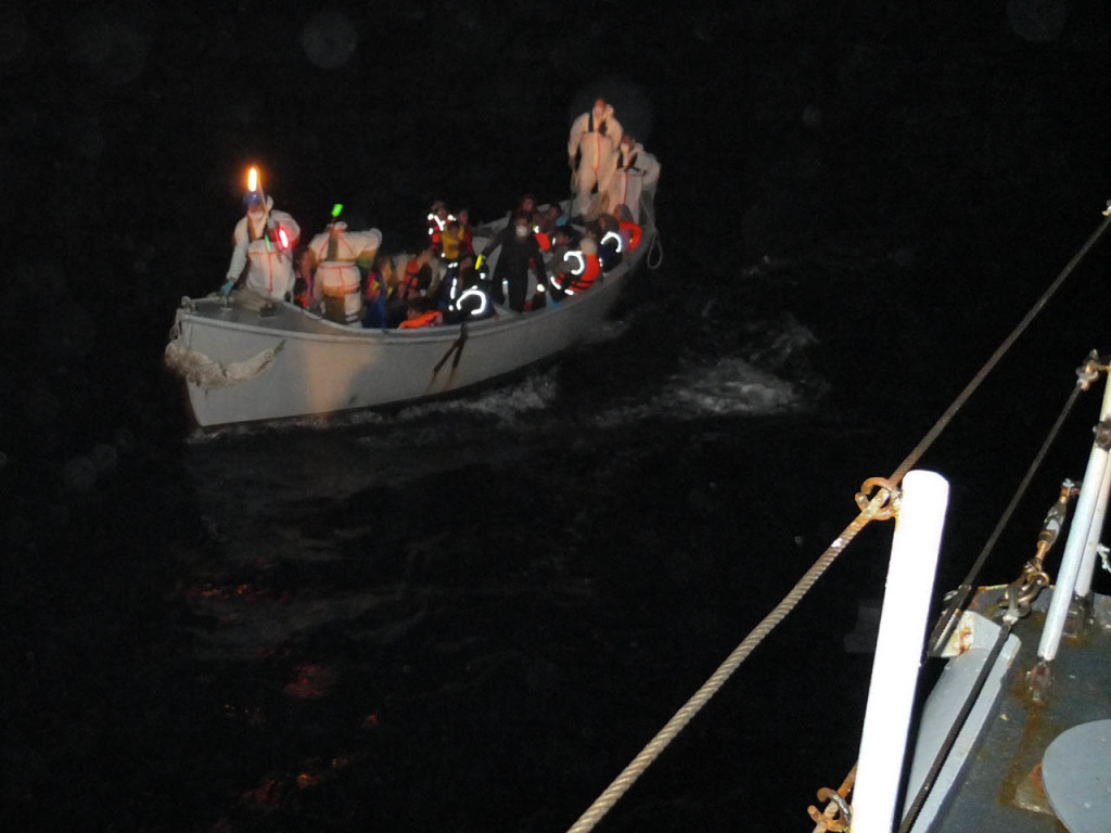 La scialuppa trasborda i primi migranti sulla Chimera